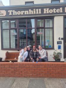 un grupo de personas sentadas en un banco frente a un hotel en Thornhill Blackpool en Blackpool