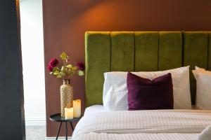 Una cama con un cabecero verde y un jarrón con flores en Berry's Loft - Central Location and Fast WIFI, en Knaresborough