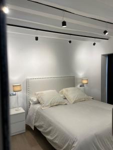1 dormitorio con 1 cama blanca y 2 lámparas en Renthas Apartamentos Rafael Premium, en Alicante