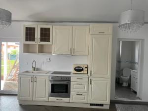 eine Küche mit weißen Schränken und einem Herd mit Backofen in der Unterkunft House Of Beyoutiful Bocsa in Bocşa