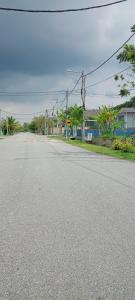 uma rua vazia numa cidade com casas e árvores em Myra Anne Home2Stay Alor Gajah Melaka em Kampong Dalong