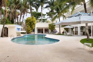 a swimming pool in front of a house with palm trees at Suites Guarujá Pernambuco in Guarujá