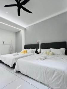 Cette chambre blanche dispose de 2 lits et d'un ventilateur de plafond. dans l'établissement Inn Homestay 1st Floor Unit, à Teluk Intan