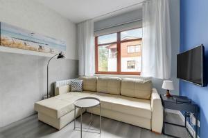 a living room with a white couch and a window at Apartament Neptun Park Gdansk Jelitkowo by Grand Apartments in Gdańsk