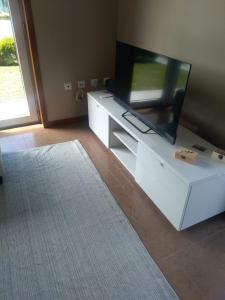 a living room with a flat screen tv on a white entertainment center at Casa T4 perto da Praia in Fão