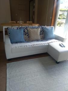 a white couch with blue pillows in a living room at Casa T4 perto da Praia in Fão