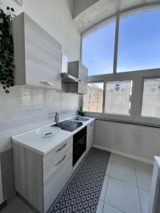 a white kitchen with a sink and a window at Gragnano_roomandapartment in Gragnano