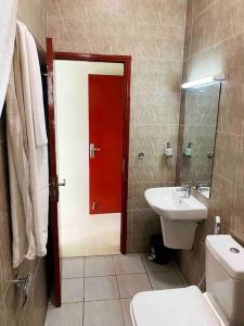 baño con aseo y lavabo y puerta roja en Mbweni Raffia Apartment en Kiembi Samaki