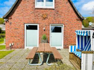a wooden picnic table in front of a brick building at Meer-Lust-Sylt Sonnenhäuschen in Westerland (Sylt)