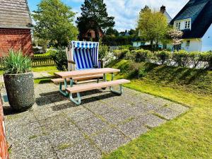 un banc en bois assis à côté d'une chaise bleue dans l'établissement Meer-Lust-Sylt Sonnenhäuschen, à Westerland