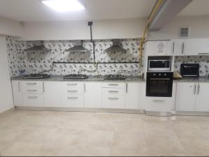 a kitchen with white cabinets and black appliances at Akademi Suit in Eskisehir