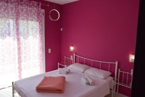1 dormitorio con paredes moradas y 1 cama con toallas en adonia villa, en Levkákia