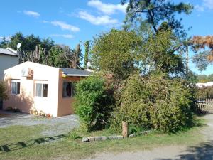 una pequeña casa blanca con un árbol en Cabañas Ronca Hue en Tandil