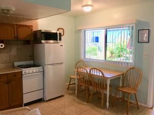 a kitchen with a table and a white refrigerator at Carousel Motel -Redington Shores in Redington Shores