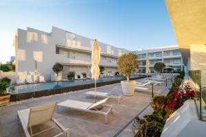 a patio with chairs and umbrellas in front of a building at Apartamentos Turísticos Gran Sol in Zahara de los Atunes