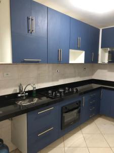 una cucina con armadi blu e lavandino di María Cristina ,ar,Wi-Fi e tv a cabo a Praia Grande