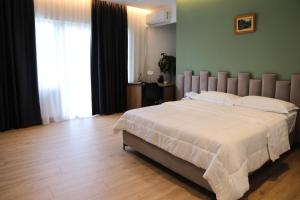 una camera da letto con un letto grande con lenzuola bianche di Hotel Blini a Shkodër