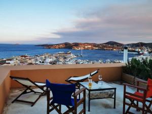 a balcony with chairs and a table with a view of a harbor at Kalypso's apt in Hermoupolis rooftop with seaview in Ermoupoli