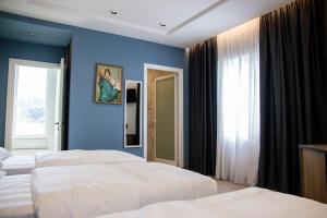 1 dormitorio con 2 camas y pared azul en Hotel Blini, en Shkodër