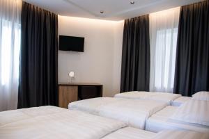 Habitación de hotel con 3 camas y TV en Hotel Blini, en Shkodër