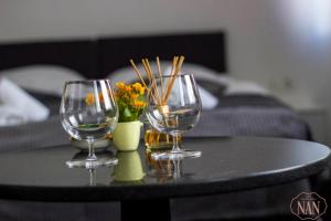 two wine glasses and a vase with flowers on a table at Apartmani NAN in Visoko