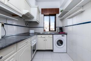 une cuisine blanche avec un lave-linge. dans l'établissement Apartamento MANTAMAR by ALGARVEMANTA, à Manta Rota