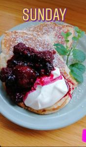a pancake with berries and cream on a white plate at Wild Atlantic Lodge Bed & Breakfast in Lahinch