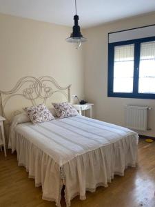 a white bedroom with a large bed with two pillows at Apartamentos Las Fuentes in Castropol