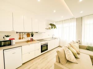 a kitchen with white cabinets and a couch in a room at A Lobeira Grande by ALÔGA in Cee