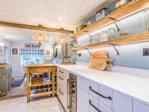 una cucina con armadi bianchi e scaffali in legno di Pass the Keys Beautiful Cottage In South Downs a Chichester