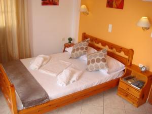 Schlafzimmer mit einem Bett mit weißer Bettwäsche und Kissen in der Unterkunft Boussetil Rooms CapAnMat in Tinos