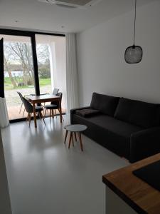 a living room with a black couch and a table at Apartamenty HELIOS in Jastrzębia Góra