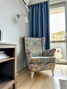 einen Stuhl im Wohnzimmer mit einem blauen Vorhang in der Unterkunft Warsaw Concierge Miedzynarodowa in Warschau