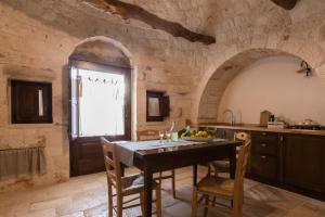 una cucina con tavolo, sedie e finestra di Almapetra Trulli Resort a Locorotondo