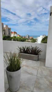 a balcony with two potted plants and a view of the ocean at Departamento Pinamar Centro Status Tower in Pinamar