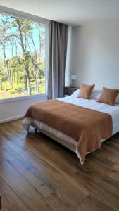 a bedroom with a large bed with a large window at Departamento Pinamar Centro Status Tower in Pinamar
