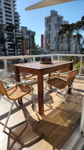 - Balcón con mesa de madera y 2 sillas en Departamento Pinamar Centro Status Tower en Pinamar