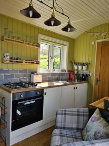 a kitchen with a stove top oven next to a couch at The bay ,luxury shepherds hut, in Dundonnell