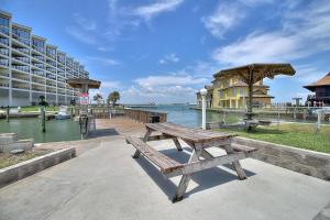 a wooden bench sitting next to the water with a building at Bay Tree D5 in Port Aransas