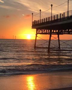 a pier with the sun setting over the ocean at The Cresswell Inn in Skegness