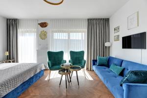 a bedroom with a blue couch and two green chairs at Blue Lagoon przy Motławie in Gdańsk