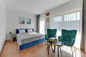 a bedroom with a bed and two green chairs at Blue Lagoon przy Motławie in Gdańsk