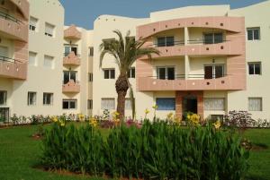 a building with a palm tree and flowers in front at MOHAMMEDIA 304 in Mohammedia