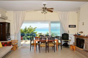 ein Wohnzimmer mit einem Tisch, Stühlen und einem Kamin in der Unterkunft Blue View of Korinthian bay villa in Lecheo in Lékhaion