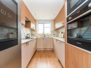 eine Küche mit weißen Schränken und schwarzen Geräten in der Unterkunft Pass the Keys Spacious Cosy Home Close To London Abbey Wood in London