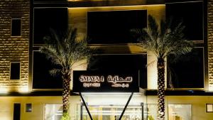 two palm trees in front of a building with a sign at Smayah Residence in Riyadh