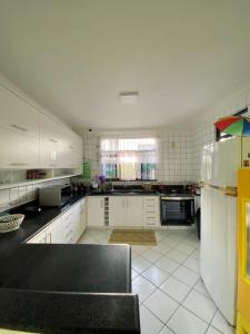 uma cozinha com armários brancos e um balcão preto em Hostel Da Jô em Ilhéus