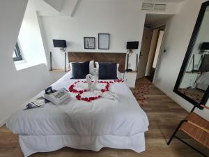 a bedroom with a white bed with red flowers on it at LA TOUR AUX CRABES près de la plage in Dieppe