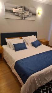 ein großes Bett mit zwei blauen Kissen darauf in der Unterkunft AL Restaurante A Lampreia in Santa Comba Dão