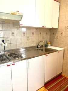 una cocina con armarios blancos y fregadero en Marina Bay View Apartment, en Bevazzana